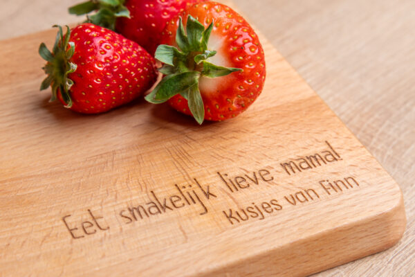 Detail van gegraveerde serveerplank met de tekst: " Eet smakelijk Lieve mama! Kusjes van Finn"