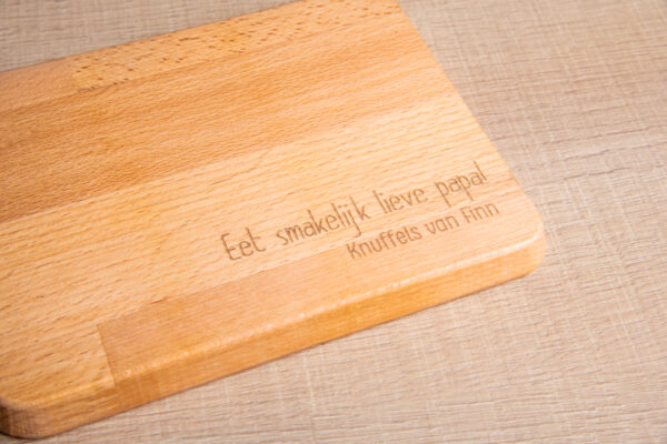 Detail van gegraveerde serveerplank met de tekst: " Eet smakelijk Lieve papa! Knuffels van Finn"